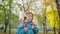 Cheerful Caucasian schoolboy in headphones dancing walking with backpack in sunny autumn park. Portrait of happy relaxed