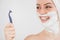Cheerful caucasian woman with a towel on her head and shaving foam on her face holds a razor on a white background