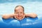 Cheerful child bathes in the pool. Little girl smiles and looks into the camera, leaning on an inflatable border