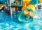 A cheerful child descends from a bright slide-tunnel into the pool and makes splashes