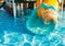 A cheerful child descends from a bright slide-tunnel into the pool and makes splashes