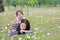 Cheerful child girl cuddle her mom lying on green field with fully fall pink flower in the garden outdoor. Happy loving family