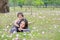 Cheerful child girl cuddle her mom lying on green field with fully fall pink flower in the garden outdoor. Happy loving family