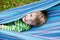 Cheerful child playing in blue hammock