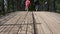 Cheerful children are holding hands running in the park over the bridge. Slow motion shot.