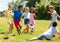 Cheerful children are jogning with ball on playground