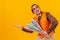 Cheerful circus performer skillfully holding a number of clubs isolated on yellow background