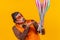 Cheerful circus performer skillfully holding a number of clubs isolated on yellow background