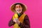 Cheerful circus performer with a sombrero holding a toy water gun on pink background