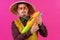 Cheerful circus performer with a sombrero holding a toy water gun on pink background