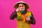 Cheerful circus performer with a sombrero holding a toy water gun on pink background