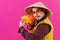 Cheerful circus performer with a sombrero holding a toy water gun on pink background