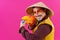 Cheerful circus performer with a sombrero holding a toy water gun on pink background