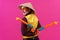 Cheerful circus performer with a sombrero holding toy water guns on pink background