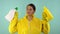 Cheerful cleaning lady in a yellow suit on a blue background. The concept of professional cleaning. The cleaner holds
