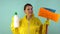 Cheerful cleaning lady in a yellow suit on a blue background. The concept of professional house cleaning. The cleaner