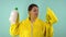 Cheerful cleaning lady in a yellow suit on a blue background. The concept of professional house cleaning. The cleaner