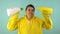 Cheerful cleaning lady in a yellow suit on a blue background. The concept of professional house cleaning. The cleaner