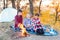 A cheerful company of two girls and a boy on a picnic in the middle of the forest. Children fry sausages on the fire, eat buns and