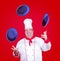 Cheerful cook juggle with ceramic plate