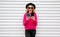 Cheerful cool girl holding two phone and looking at them on white wall