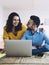 Cheerful couple browsing laptop, smiling and looking at each other at home