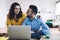 Cheerful couple browsing laptop, smiling and looking at each other at home