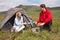 Cheerful couple cooking outdoors on camping trip