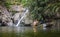 Cheerful couple enjoying river bath by waterfall