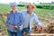 Cheerful couple of farmers standing on vegetable garden