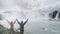 Cheerful Couple Raising Hands At Godafoss Waterfall - Happy Success Hiking