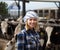 Cheerful cowgirl working with milking herd at cowhouse in farm