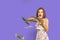 Cheerful and crazy European teenage girl throws money in her hands on a purple background