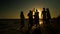 Cheerful crowd dancing on the beach. They jump in the sun. People are having fun. They are happy. Silhouettes of people