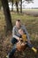 cheerful dad and son are sitting on a stump in forest, holding a wicker straw basket filled with edible mushrooms