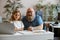 Cheerful daddy and cute little do homework together sitting at table with laptop