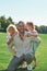 Cheerful daddy smiling at camera, posing together with two cute little kids, daughter and son on grass field in summer