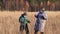 Cheerful dance of a woman and a boy with masks on their faces in the tall grass.