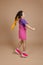 Cheerful dancing small female child with two yellow kanekalon pigtails jumping looking away smiling in pink jumpsuit