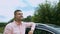 Cheerful delighted man leaning on his car outdoors