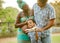 Cheerful diverse pregnant parents with adorable little son embracing in park