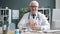 Cheerful doctor senior man touching glasses smiling looking at camera in clinic