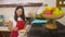 Cheerful domestic cooking - young happy and beautiful Asian Korean home cook woman in red apron reading healthy recipe in mobile