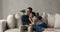 Cheerful dreamy spouses relaxing hugging sitting on sofa