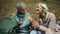 Cheerful elderly couple enjoying their touristic lunch in the wood