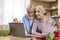 Cheerful Elderly Spouses Making Video Call With Laptop In Kitchen Interior