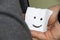 A cheerful emoticon is drawn on a piece of paper in the hands of a woman, a good mood, joy