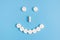 Cheerful emoticon from medical pills on a blue background. The concept of prevention of viral diseases