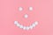 Cheerful emoticon from medical pills on a pink background