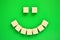 Cheerful emoticon from refined sugar on a green background